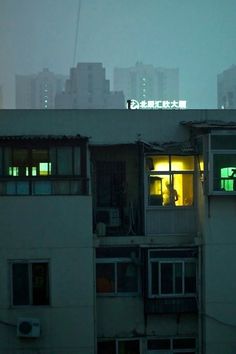 an apartment building with the lights on in the window at night, and skyscrapers in the background