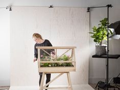 a woman standing in front of a wooden planter with plants inside and behind it