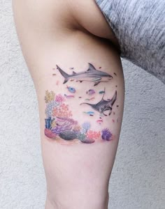 a woman with a tattoo on her leg that has dolphins and corals all over it