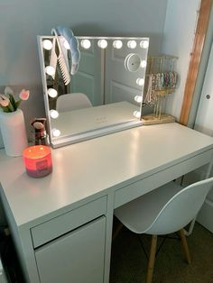 a white desk topped with a vanity mirror and a lit up candle on top of it