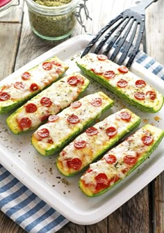 zucchini stuffed with pepperoni and cheese on a white plate next to a fork