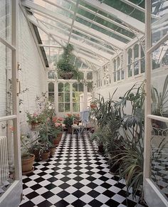 an indoor greenhouse filled with lots of plants and potted plants on the side of the building