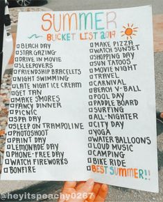 a person holding up a sign with the words summer bucket list written in front of them