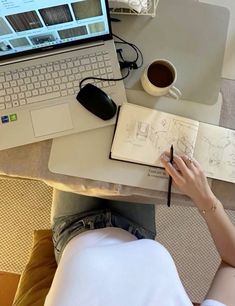 a person sitting at a desk with a laptop and notebook in front of them, writing on paper