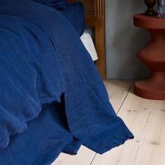 a blue comforter on a bed in a room with wood flooring and furniture