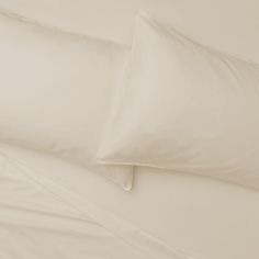 two white pillows sitting next to each other on top of a bed with sheets and pillow cases