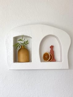 two small white shelves with oranges and a cat figurine on one shelf