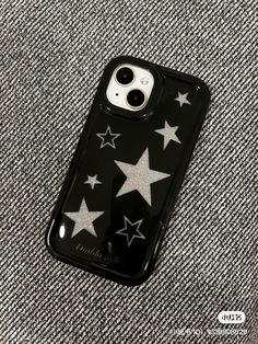 an iphone case with silver stars on it sitting on a gray fabric background, showing the back and sides of the phone