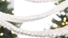 a white rope hanging from the ceiling next to a christmas tree with lights on it