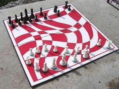 a giant chess board with white and black pawns on the ground next to it