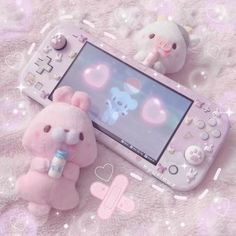 a pink teddy bear sitting next to a nintendo wii game controller on top of a blanket