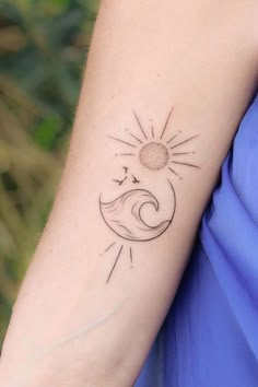 a woman's arm with a sun and moon tattoo on the left side of her arm