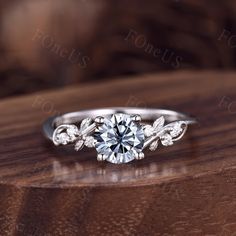 a diamond ring with leaves on it sitting on top of a wooden table in front of the camera