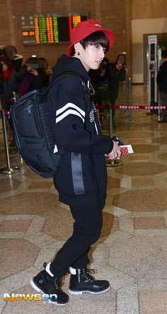 a boy in a red hat and black jacket with a back pack at an airport