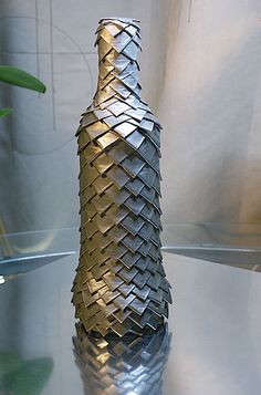 a vase that has been made out of metal strips and is sitting on a glass table