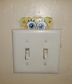 a white light switch with two blue eyes on it's cover and a spongebob head