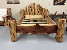 a bed made out of wooden logs in a room with white walls and flooring