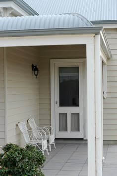 a white chair sitting on top of a patio next to a door and window in front of a house