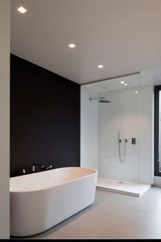 a large white bath tub sitting next to a window in a room with black walls