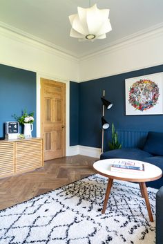 a living room with blue walls and white rugs on the floor, wooden furniture