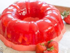 there is a bundt cake with strawberries on the side and another strawberry in the background