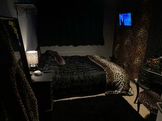 a leopard print comforter on a bed in a dark room with a television and dresser