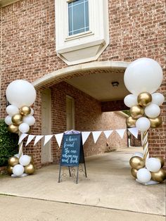 an entrance to a building decorated with white and gold balloons