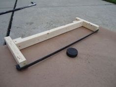 a wooden bed frame sitting on top of a cement floor next to a black rock