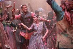 a group of people celebrating with colored powder on their faces and arms, dancing in the rain