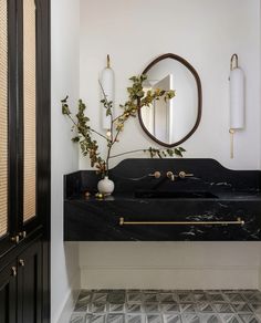 a black and white bathroom with a mirror, sink and vase on the counter top