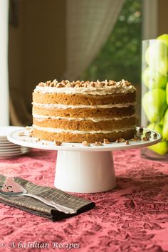 a cake sitting on top of a white plate next to a knife and bowl of fruit