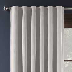 a white curtain hanging on the side of a window in front of a blue wall