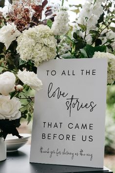 a sign that says to all the love stories that came before us next to some flowers