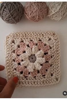 crochet granny square with balls of yarn in the background