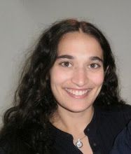 a woman with long dark hair smiling at the camera while wearing a black jacket and white shirt