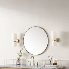 a bathroom with two sinks and a round mirror on the wall above it, along with other accessories