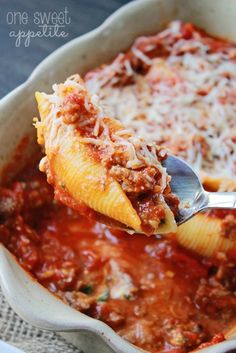 a spoon full of lasagna sauce being lifted from a casserole dish