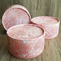 three pink flowered dishes sitting on top of a wooden table