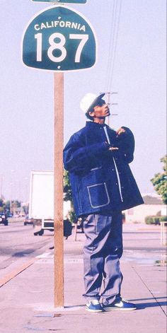 a man standing on the sidewalk next to a street sign that says california, 1876