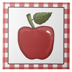 an apple on a checkered red and white tablecloth with a green leaf in the center