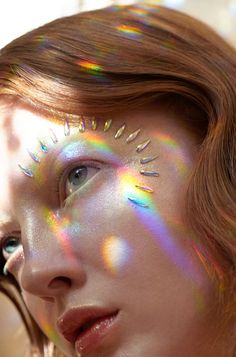 a woman's face with holographics on it and her hair blowing in the wind