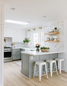 a kitchen with white and gray cabinets and counter tops, two stools in front of the island