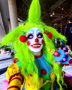 a clown with bright green hair and makeup