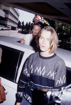 two men standing next to each other in front of a car