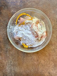 a glass bowl filled with powdered sugar and orange peels on top of a wooden table