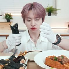 a person sitting at a table with some food in front of him and holding up their hands