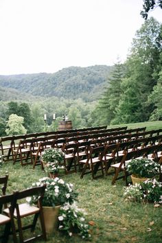 an outdoor ceremony set up with wooden chairs and flowers