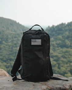 a backpack sitting on top of a rock with the american flag patched on it