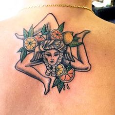 the back of a woman's shoulder with flowers and fruit around her neck,