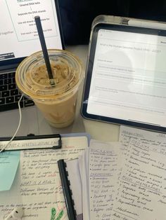 a laptop computer sitting on top of a desk next to a cup of coffee and papers